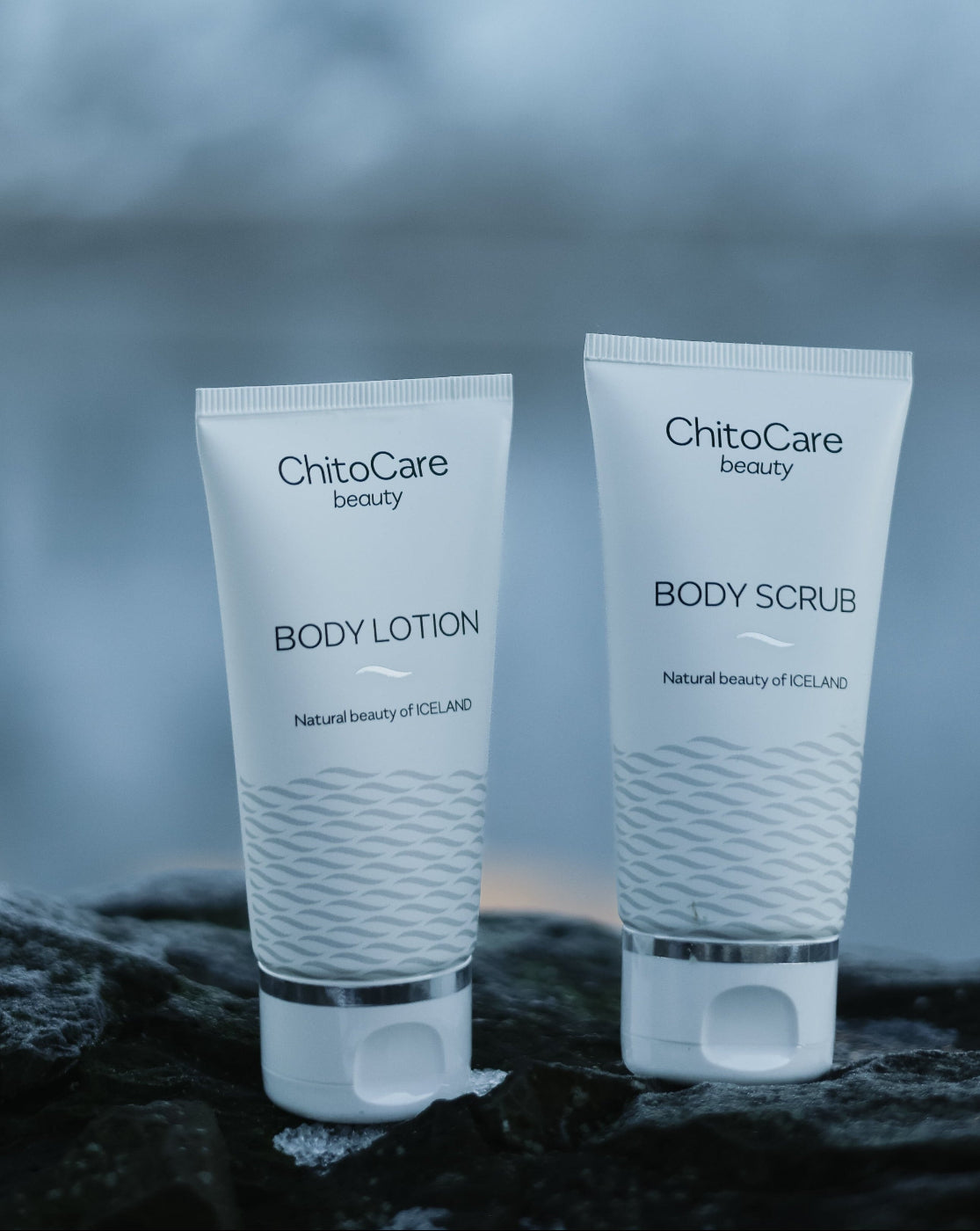 Two tubes of ChitoCare body care products on a rock with a blurred natural background