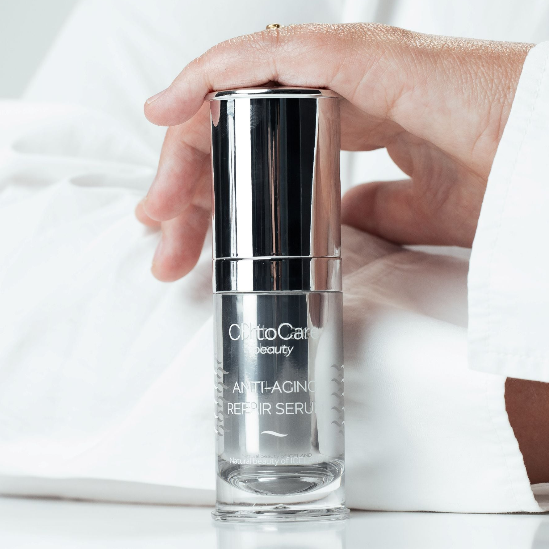 Hand holding a skincare serum bottle labeled 'ChitoCare' on a white surface.